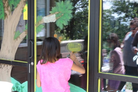 A student paints on the front doors of a visitors center