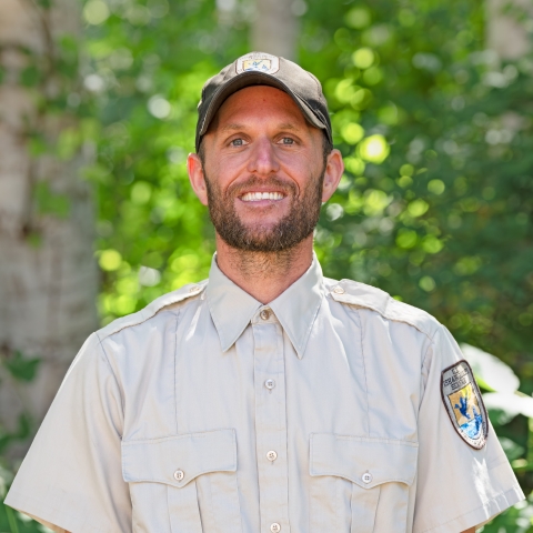 Service staff member, Brady Foreman, in uniform with trees in the background. 