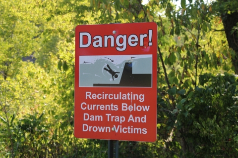 Sign that says "Danger! Recirculating currents below dam trap and drown victims."