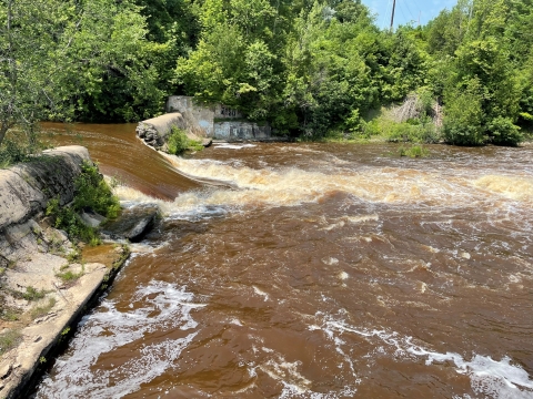 a breached dam with river water flowing through the gap