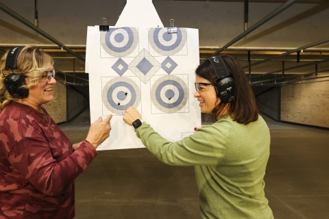 Two women examine indoor targets at indoor target range. 