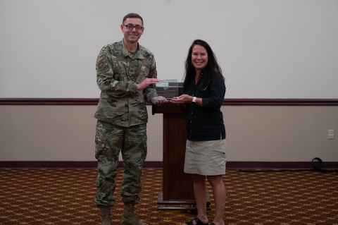 A man in fatigues accepts an award from a woman in a U.S. Fish and Wildlife Service shirt