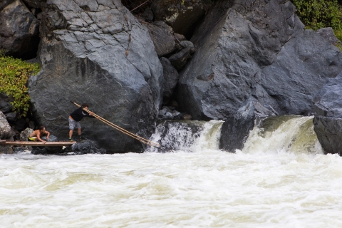 Two Karluk Tribal Members Fishing for Salmon along a short waterfall portion of a river with large rocky banks. 