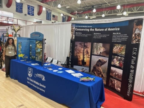 USFWS employee standing next to information booth set up at event