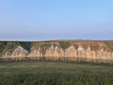 landscape of steep bluffs on a river edge and boreal forest