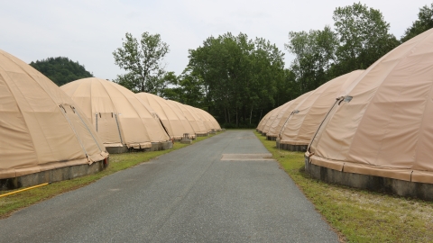 A paved road lined with circular, canvas-domed fish rearing tanks. 