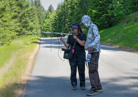 Jakob Bengelink teaching Service intern, Bethany Fackrell to use radio telemetry equipment on a paved roadway near the Elwha River.