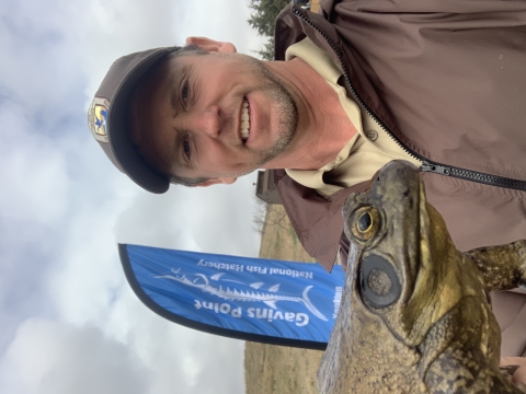 A uniformed Fish and Wildlife Service biologist holds a large bullfrog