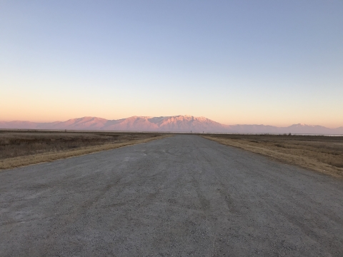 Sun kissed mountains in the distance with gravel road headed toward them.