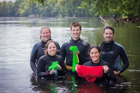 People standing in a river wearing wetsuits 