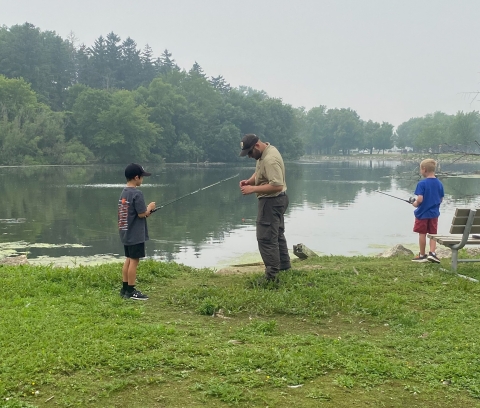 Adult assisting children with fishing. 