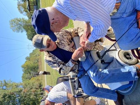 Two elderly men removing a hook from a fish