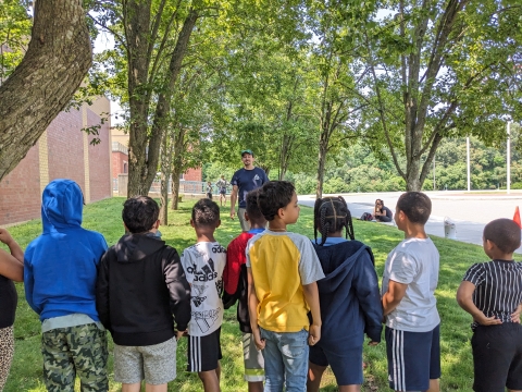 a group of children line up in a park facing a man 