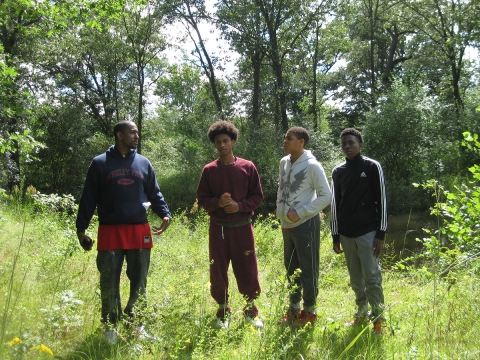 four young men stand in an open woodland