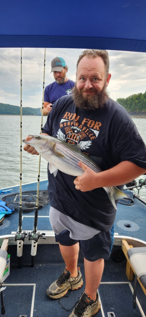 Man poses with striped bass on boat