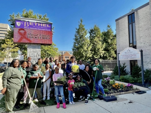 group poses in front of garden beneath sign reading Bethel African Methodist Episcopal Church/breast cancer awareness month