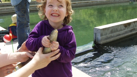 Young girl smiling, holding her fishing catch