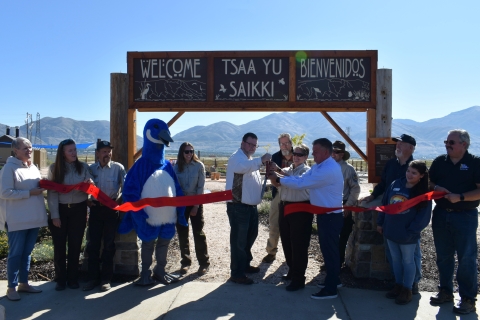 Grand opening ribbon cutting ceremony with officials from USFWS, Box Elder County, Box Elder County Tourism and Friends of the Bear River Refuge. Cutting ceremony in front of of the welcome sign with a mountain background