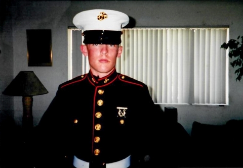 A young man wearing U.S. Marine Corps dress blue uniform with a white hat.
