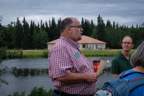 Scott Faulkner, in a white and red shirt, stands in profile in the foreground of the Chena River.