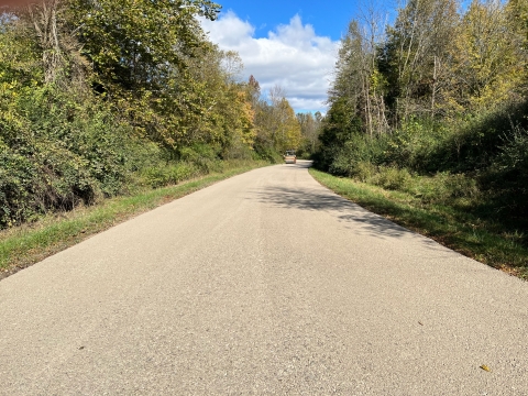 A view of newly paved road leading through treed landscape.