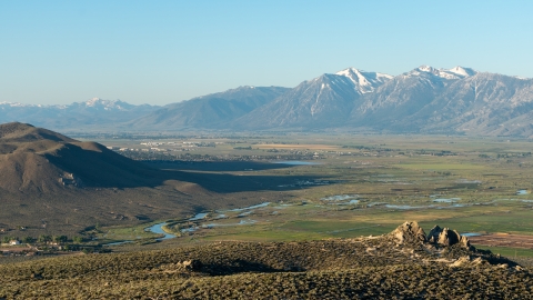 A view of the Carson Valley during sunrise. Mountains are off in the distance while a river cuts through the sagebrush filled valley below.