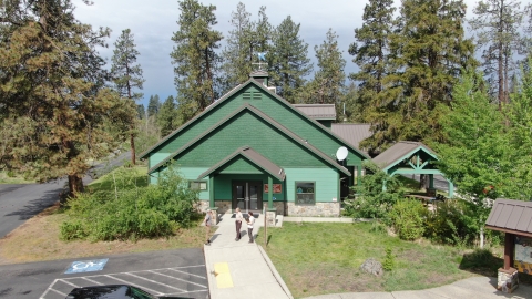 Aerial view of the Turnbull NWR administrative offices. Two staff members talk with a visitor out front.