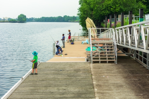 Several young people fishing off a public deck