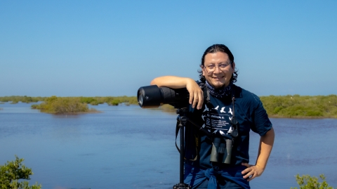 Ernesto Gomez poses with his camera for a portrait in front of a wetland in Yucatan