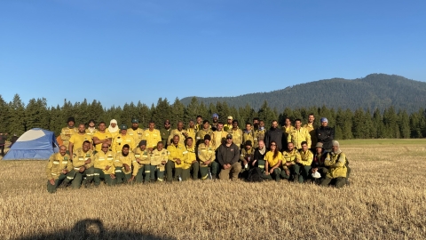 A group of firefighters pose for a photo as a group in a meadow