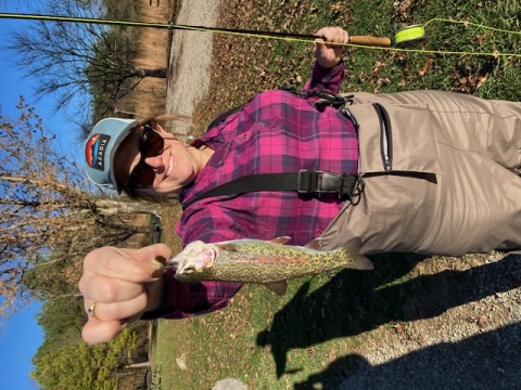 Woman posing with Rainbow trout and fishing gear