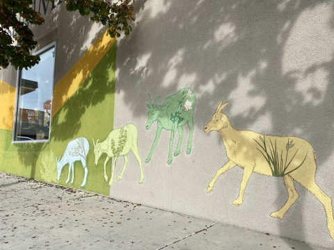 blue, green and yellow paintings of Sierra Nevada bighorn sheep grazing appear on a wall in Bishop, CA