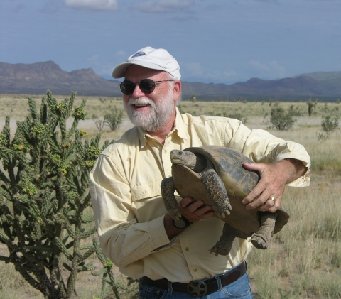 A man holding a large tortoise.