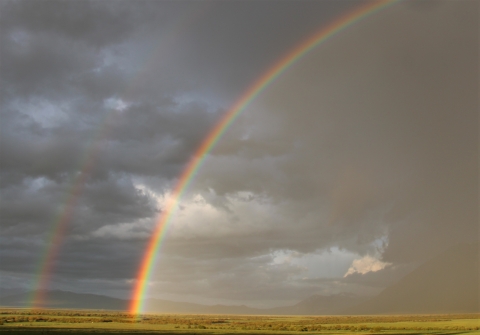 A double rainbow in a green valley.