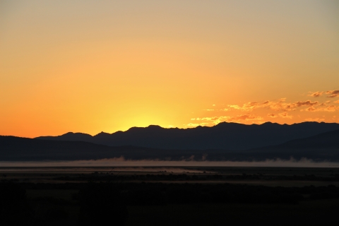 An red-orange early sunrise with mountainous background.