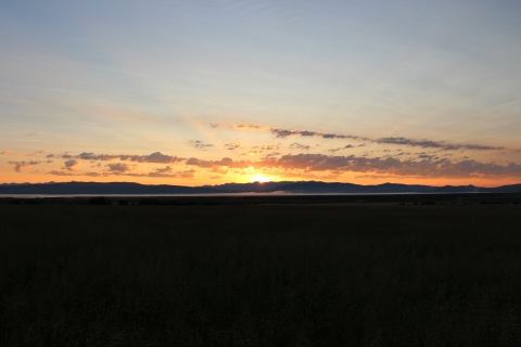 A summer sunrise with yellow sun rays illuminates the sky and clouds