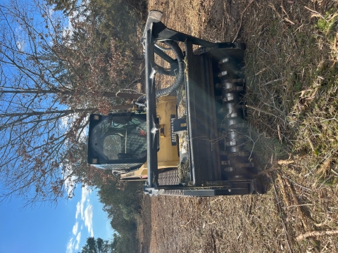 Skid Steer with masticator attachment sits on masticated brush.