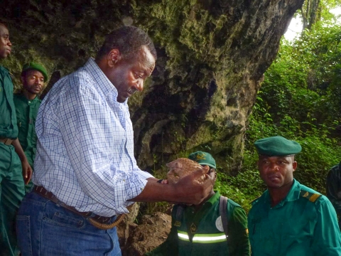 A man holds a pangolin, with law enforcement officers looking on
