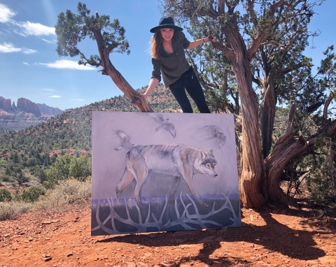 Woman holding a painting of a wolf 