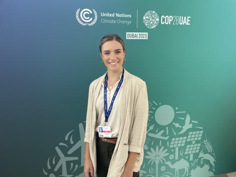 a woman standing in from of a wall that says COP28UAE United Nations Climate Change