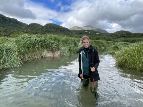 A woman in waders stands in a river
