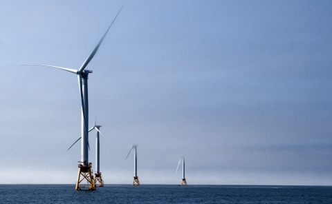 four white metal turbines rise from the ocean