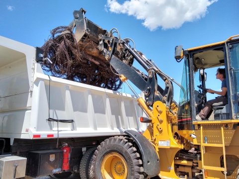 A front end loader dumps a load of refuse into a dump truck.