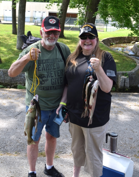 two veterans hold up the Rainbow trout they caught.