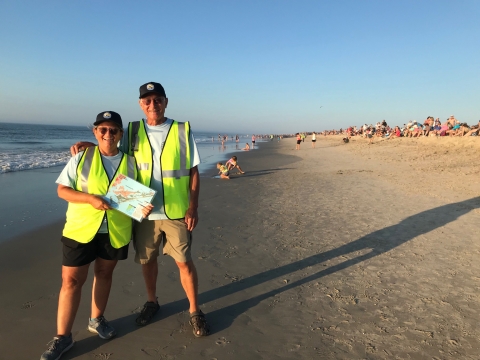 Two volunteers pose with a refuge map on the beach