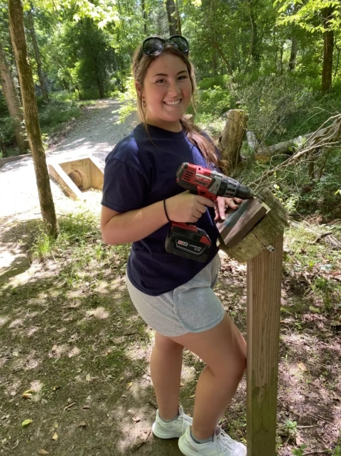 Girl volunteering work on a nature trail sign