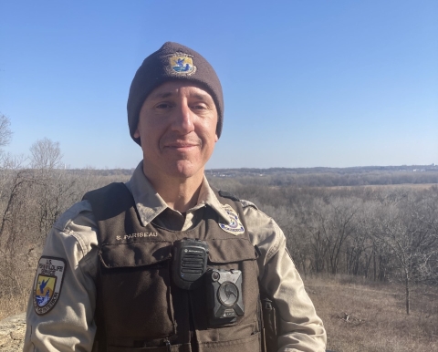 A man in the uniform of a U.S. Fish and Wildlife Service federal wildlife officer faces the camera