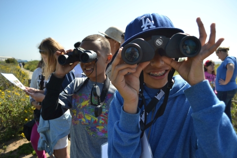 Smiling youngsters use binoculars to look at birds at San Diego Bay National Wildlife Refuge.
