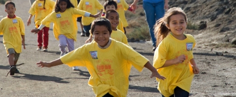 Kids in yellow shirts run at Don Edwards San Francisco Bay National Wildlife Refuge, while on an elementary school field trip.