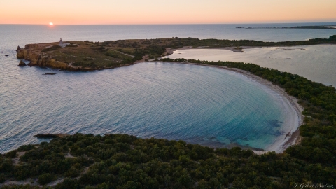 Aerial view of a beach with the sun setting in the background